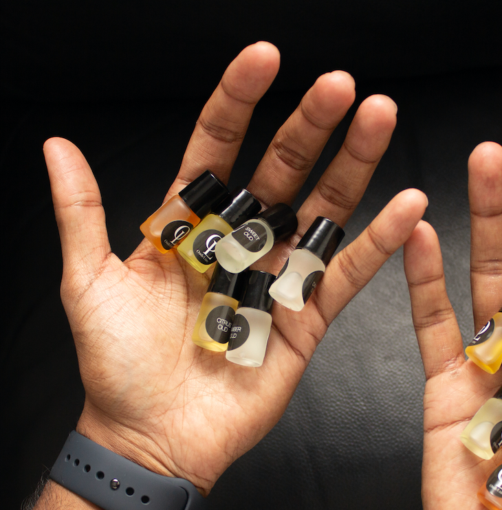 Hand holding multiple small bottles of oud